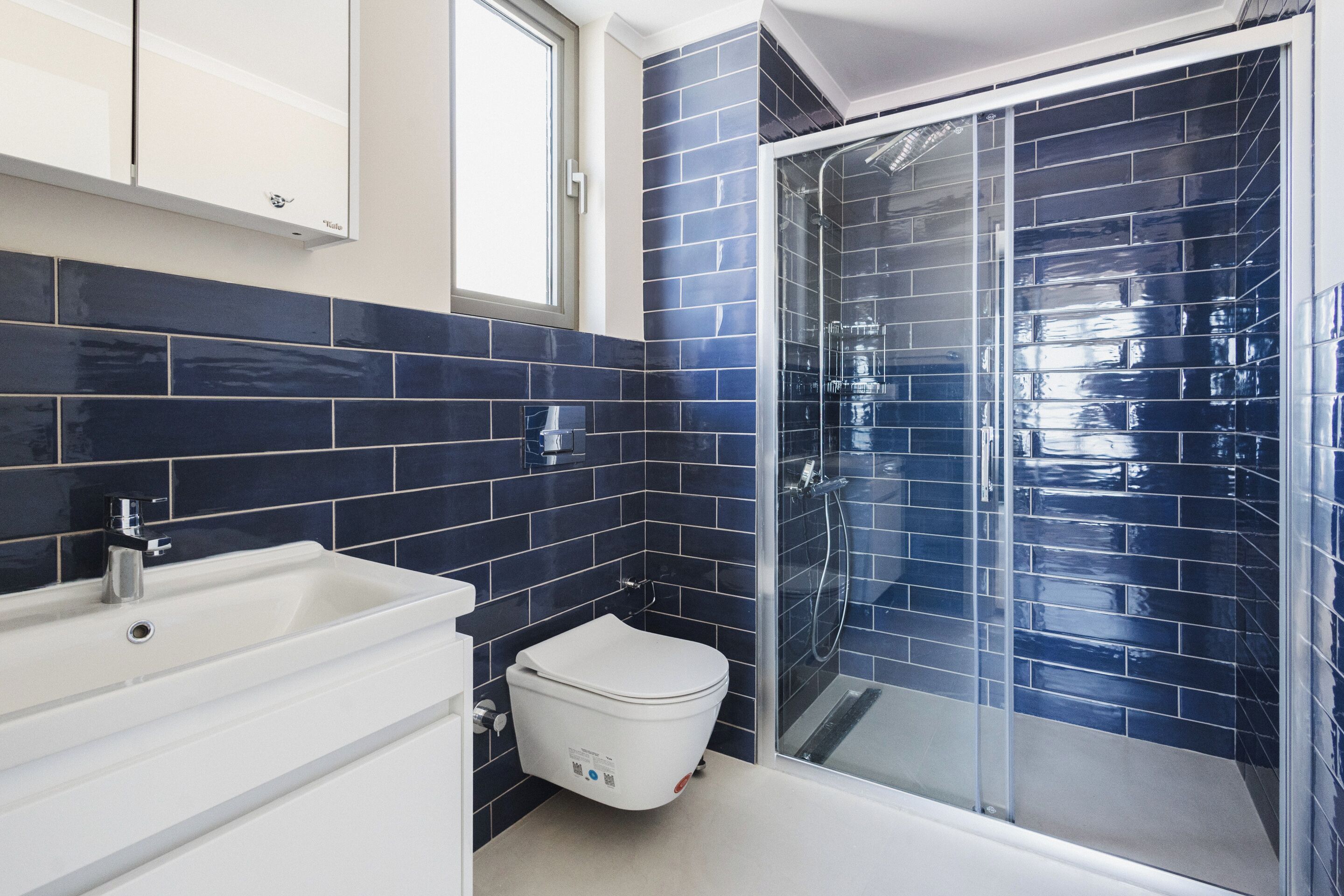 Un bagno moderno con lavandino bianco, vaso igienico bianco e cabina doccia in vetro.