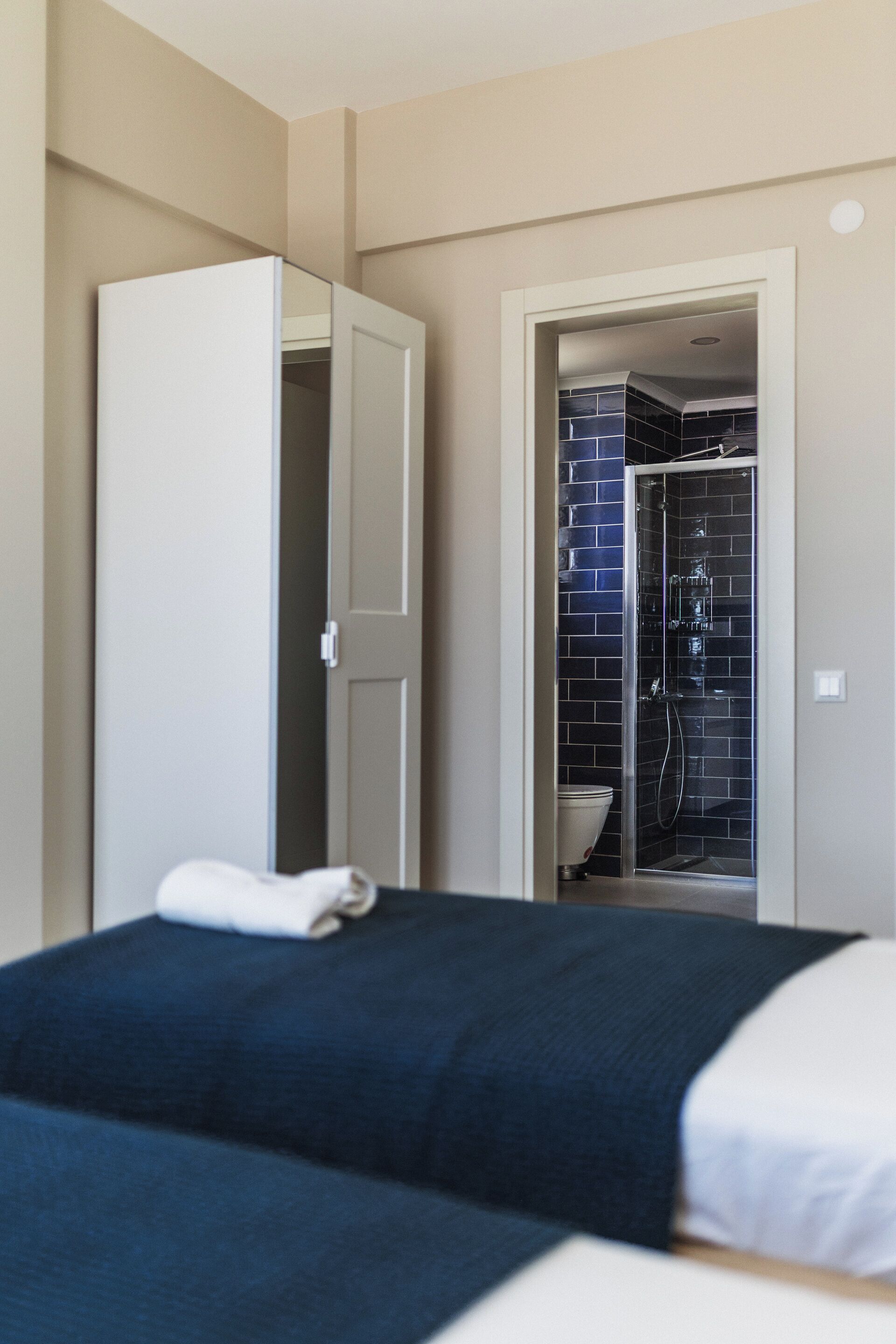 A hotel room with a bed, a bathroom with a shower, and a toilet.