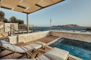 Ein Poolbereich mit Liegestühlen und Meerblick.