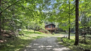 Une cabane entourée d’une forêt, avec un chemin de gravier menant à celle-ci.
