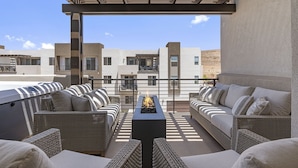 A rooftop terrace with wicker furniture, a fire feature, and a view of buildings in the background. - The Crash Pad 5 Bedroom Townhouse (St. George)
