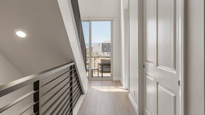 A modern interior with a sloped ceiling, a staircase, and a view to an outdoor patio area. - The Crash Pad 5 Bedroom Townhouse (St. George)