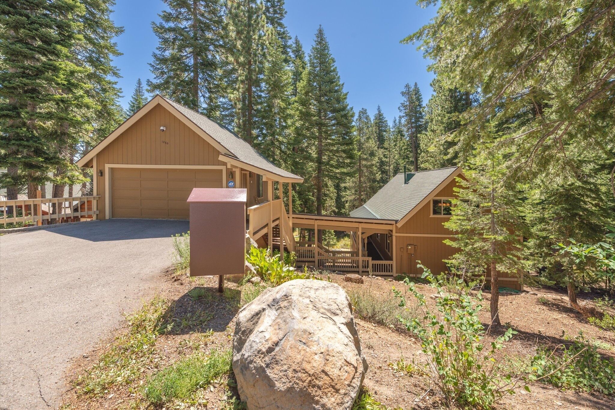 Une cabane en bois avec un garage, entourée de grands pins.