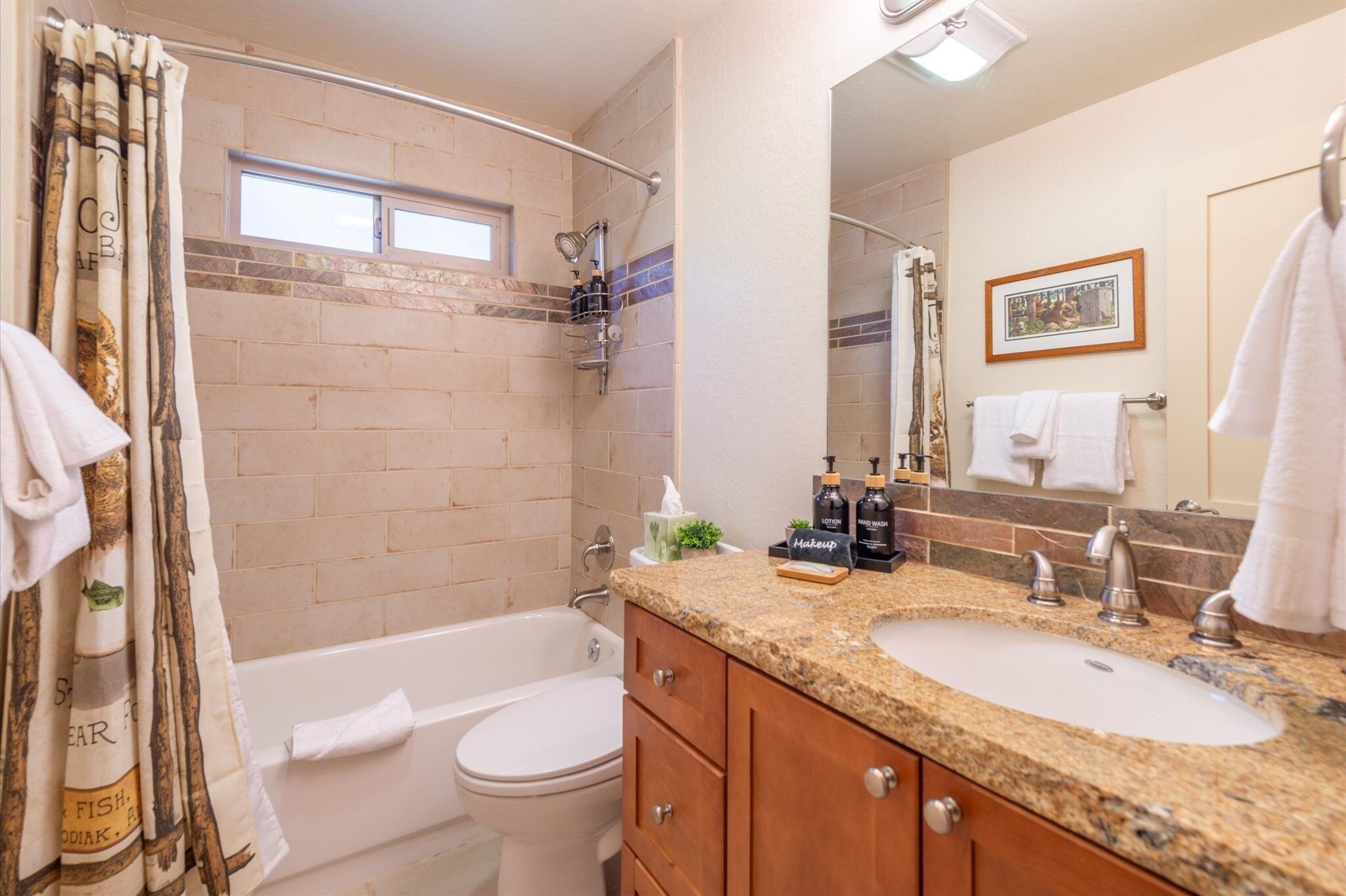 A bathroom with a bathtub, toilet, vanity with a sink, and a shower area.