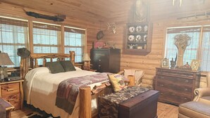 Un dormitorio rústico con una cama de madera, un aparador, una mesita de noche y un estante montado en la pared con objetos decorativos.