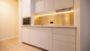 A modern kitchen with white cabinetry, a built-in oven, and under-cabinet lighting. - Elegant Apt With AC - 2br-6p -palais Garnier (Paris)