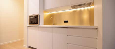 A modern kitchen with white cabinetry, a built-in oven, and under-cabinet lighting.