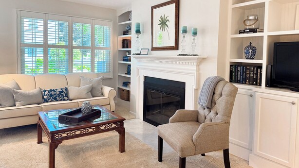 A living room with a fireplace, a sofa, a chair, and a bookshelf.