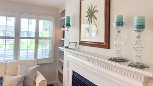 A living room with a fireplace, a framed botanical print, and three candle holders.