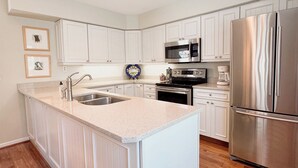 Una cocina moderna con armarios blancos, electrodomésticos de acero inoxidable y una isla central.