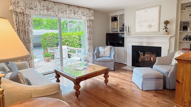 Una sala de estar acogedora con chimenea, televisor y comedor con vistas al jardín.