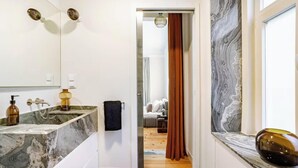 Une salle de bain moderne avec un lavabo en marbre, un porte-serviettes et une porte de douche en verre.