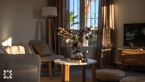 A living room with a sofa, a round table with a vase of flowers, a lamp, and a television. - Villa CELENZA by Abahana Villas (Benitachell)
