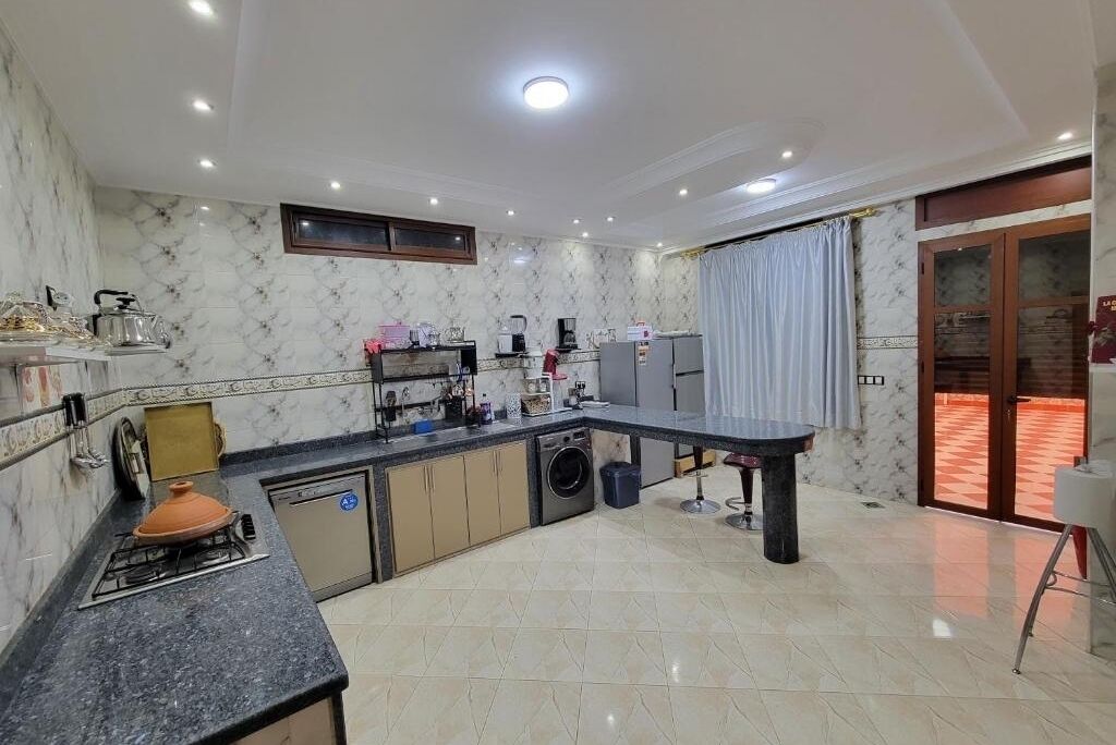 A modern kitchen with a built-in oven, a washing machine, and a coffee maker.