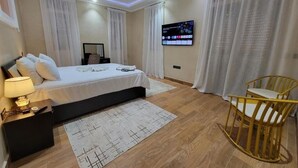 Une chambre d’hôtel moderne avec un grand lit, un téléviseur fixé au mur et un plancher en bois.