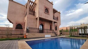 Un immeuble doté d’une piscine, de balcons et surplombant un ciel dégagé.