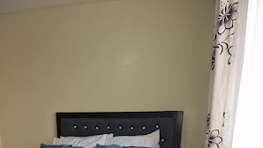 A neatly made bed with a blue and white duvet, a white pillow, and a rolled white towel. - Double K Loft 1-bedroom apartment in Nairobi (Nairobi)