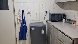A compact kitchen with a refrigerator, microwave, and wooden cabinets. - Double K Loft 1-bedroom apartment in Nairobi (Nairobi)