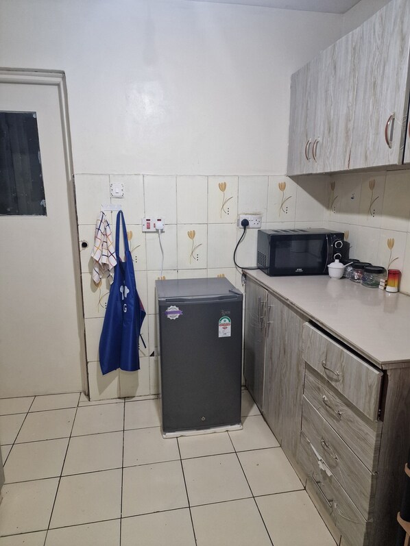 A compact kitchen with a refrigerator, microwave, and wooden cabinets.
