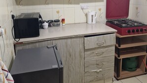 A compact kitchen with light wood cabinets, a gas stove, a microwave, and a small refrigerator. - Double K Loft 1-bedroom apartment in Nairobi (Nairobi)