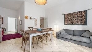 Un salon moderne comprenant un coin repas, un canapé gris et un élément décoratif mural.