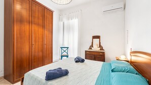 Une chambre à coucher avec un lit, une armoire en bois, une petite table avec une lampe et une chaise.