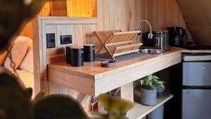 Eine kleine Küche mit Holzwänden, einem Spülbecken und einem kleinen Kühlschrank.