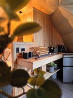 Una cocina compacta con paredes de madera, un lavamanos y un refrigerador pequeño.