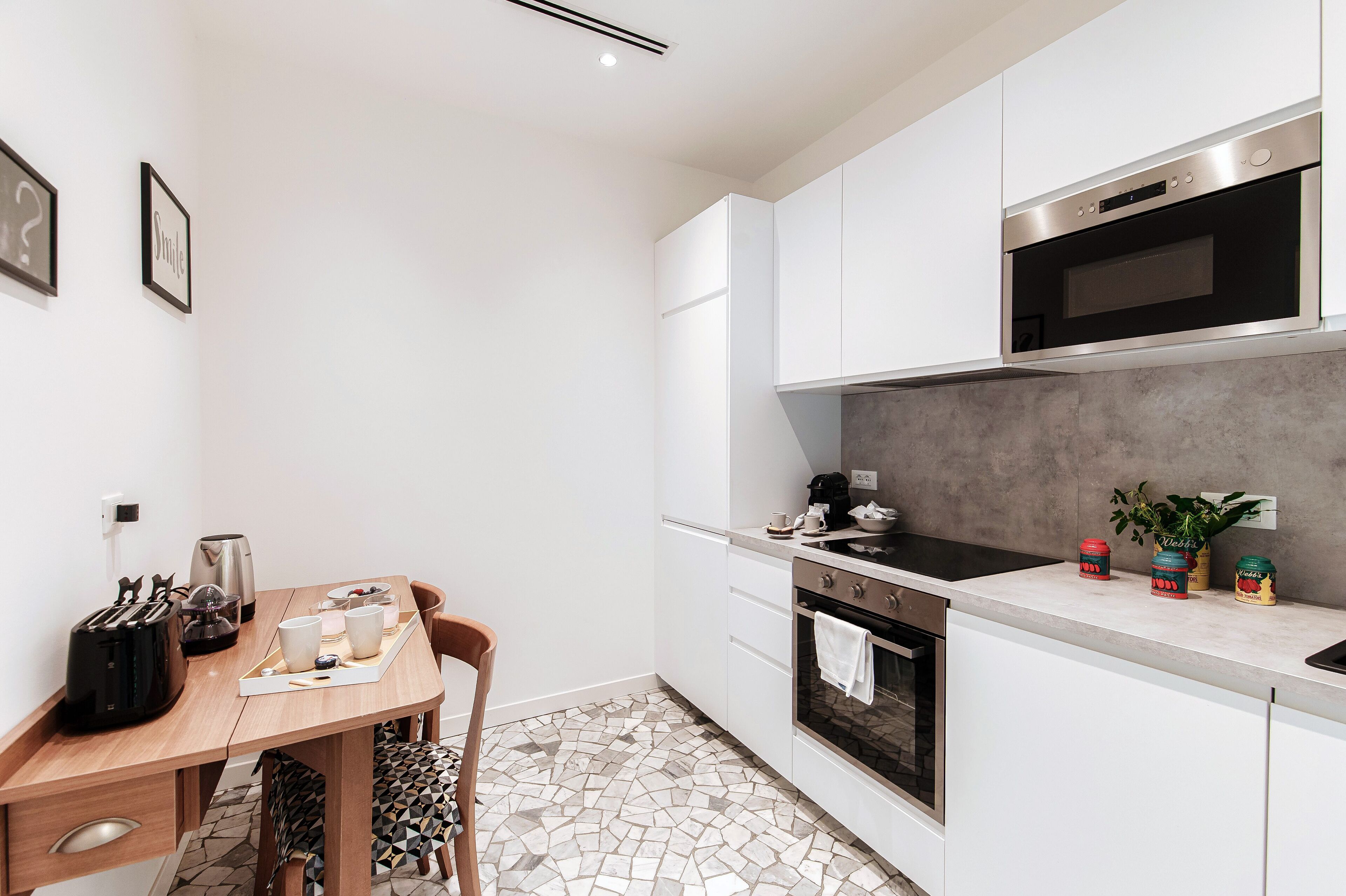 Una cocina moderna con armarios blancos, estufa negra y piso de baldosas.