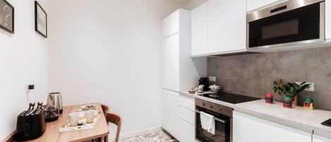 Una cocina moderna con armarios blancos, estufa negra y piso de baldosas.