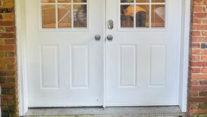 Une porte double blanche avec des panneaux de verre, un clavier pour ouvrir la porte et une poignée de porte en métal.