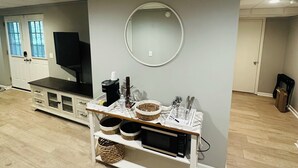 Une pièce avec un meuble blanc, un miroir rond et un téléviseur posé sur un support.