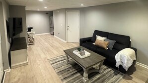 Un salon moderne avec un canapé de couleur foncée, une table basse et un meuble pour la télévision.