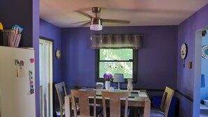 A dining area with a table, chairs, a ceiling fan, and a window with a view of greenery. - Come recharge and be minutes from the Delaware Bay, Cape May & Wildwood Beaches. (Lower Township)