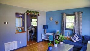 A living room with a blue sofa, a coffee table, and a dining area with a table and chairs. - Come recharge and be minutes from the Delaware Bay, Cape May & Wildwood Beaches. (Lower Township)