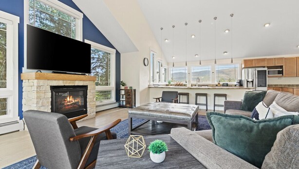 A modern living room with a fireplace, a large flat-screen TV, and a cozy seating area.