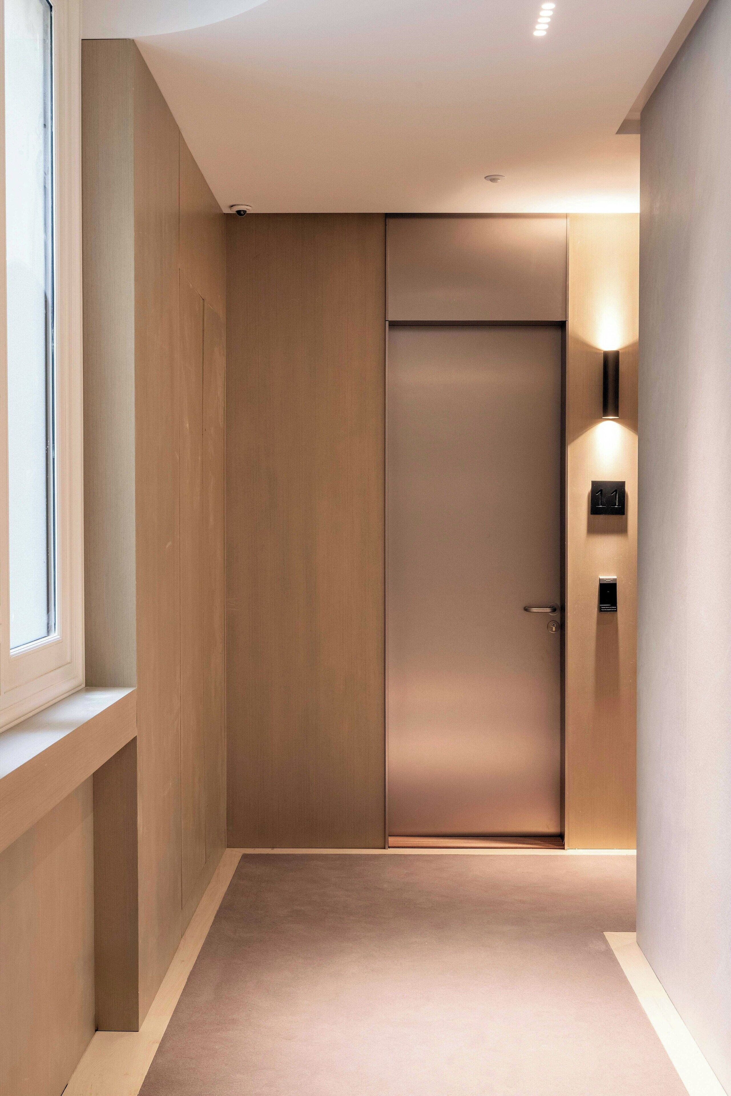 En moderne elevator med minimalistisk design, et synligt dørhåndtag og en vægmonteret lampe.
