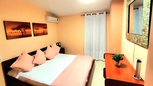 Ein Schlafzimmer mit einem Bett, einem Nachttisch, einem Spiegel und zwei an der Wand befestigten Bildern.