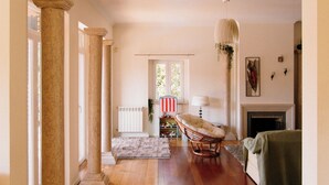 Un salon spacieux doté de parquets en bois, d’une cheminée et d’un coin salon comprenant un fauteuil et un canapé.