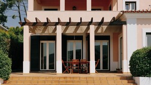 Une maison à deux étages avec une piscine, un patio couvert avec une table et des chaises, et un petit jardin.