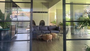 A modern interior with a glass partition, a dark-colored sofa, and a ceiling fan. - Modern Studio | Fast WiFi, Netflix | Short walk to IT Park (Cebu City)