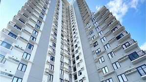 A high-rise building with multiple balconies, a swimming pool, and a covered area with chairs. - Modern Studio | Fast WiFi, Netflix | Short walk to IT Park (Cebu City)
