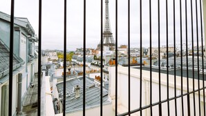 A view of the Eiffel Tower from a high vantage point, with buildings and rooftops in the foreground.