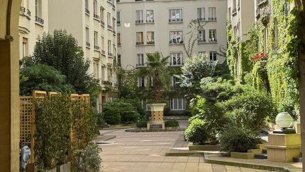 A courtyard with a central fountain, surrounded by multi-story buildings with balconies.