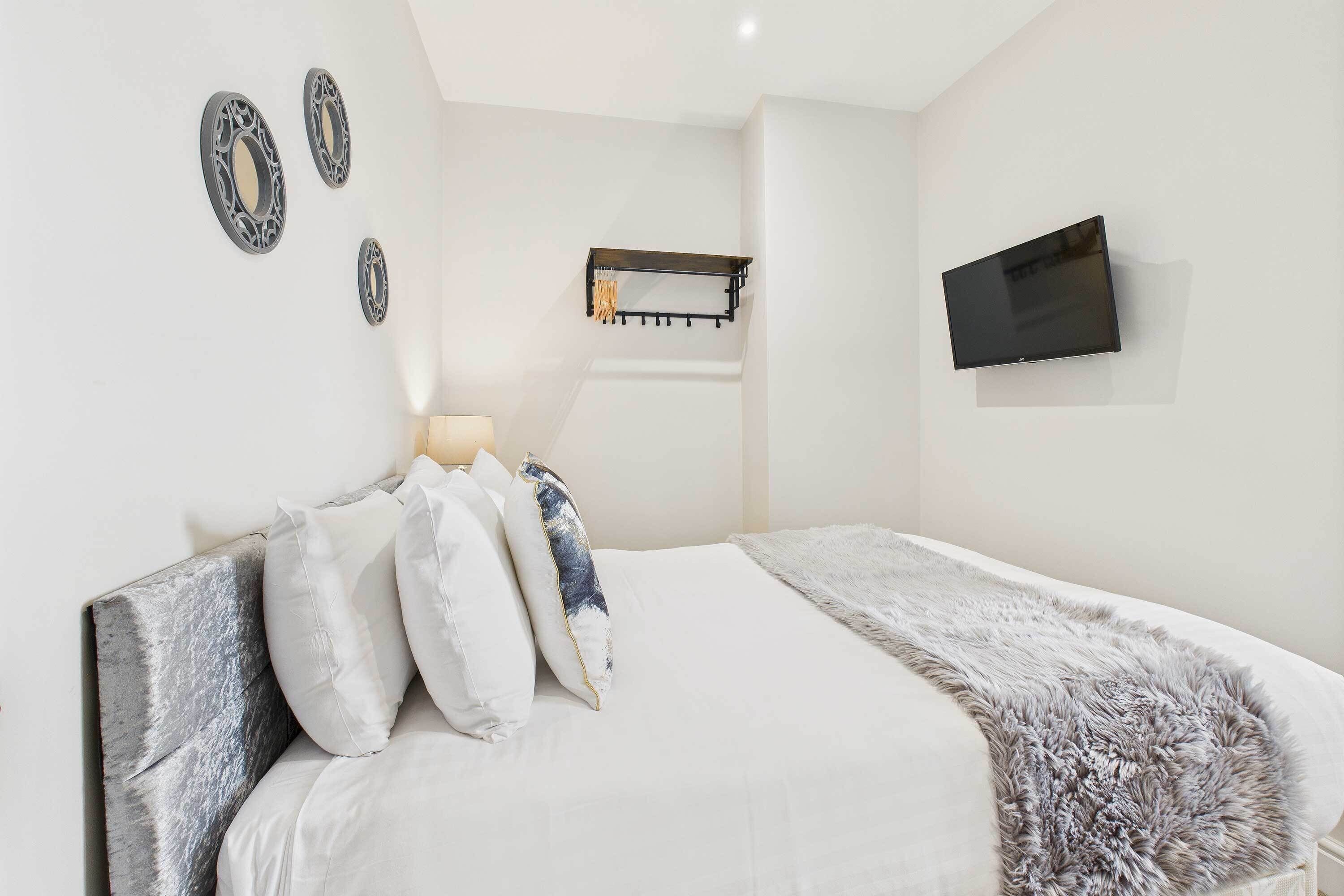 A modern bedroom with a bed, a mounted TV, and decorative wall art.