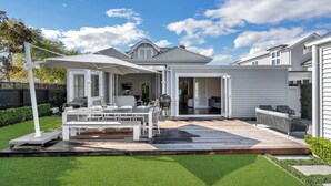 Une maison moderne dotée d’un patio, d’un espace salon extérieur et d’une pelouse bien entretenue.