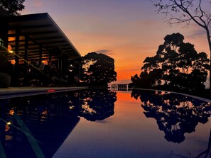 A serene outdoor pool area with a clear view of the sunset, surrounded by trees and a building structure. - Waterfall View, Mountainside Private Studio (San José)