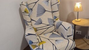 A chair with a leaf pattern, a lamp, and a small round table. - Verdi HOUSE - Relaxation and Flavors (Savigliano)