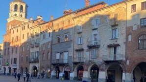 A historic building with multiple arches and a clock tower. - Verdi HOUSE - Relaxation and Flavors (Savigliano)