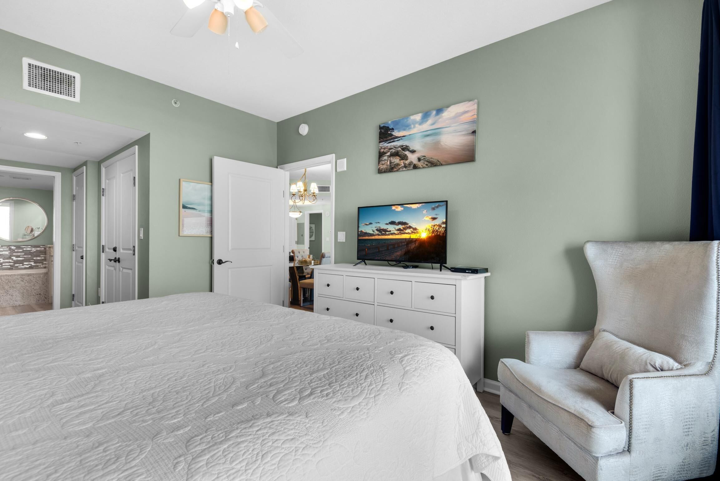 Een slaapkamer met een groot bed, een televisie, een stoel en kunstwerken aan de muren.